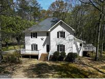 White two-story house with large deck and surrounding trees at 2095 Sw Flat Shoals Rd, Conyers, GA 30094