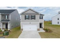 Two-story house with gray siding, a two-car garage, and landscaping at 11996 Conrad Cir # 128, Hampton, GA 30228