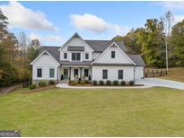 Two-story farmhouse with white siding, stone accents, and a spacious lawn at 119 Griffin Way, Canton, GA 30115