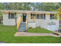 Ranch style home with a brick facade, attached garage, and well-manicured lawn at 2816 Cloverhurst Dr, East Point, GA 30344