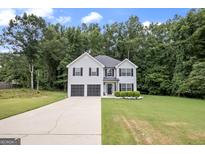 Two-story house with gray siding, dark garage doors, and a landscaped lawn at 427 Blackbird Way, Hampton, GA 30228