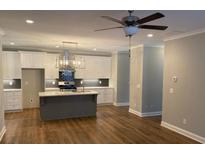 Open concept kitchen with island, white cabinets, and hardwood floors at 2120 Railyard Avenue # 13, Grayson, GA 30017
