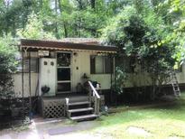 Mobile home exterior with covered porch and mature trees at 1940 Lee Rd, Lithia Springs, GA 30122