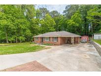 Brick ranch home with carport and storage shed, nestled in a wooded area at 1563 Dresden Ne Dr, Atlanta, GA 30319