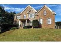 Brick two-story house with stone accents and landscaped yard at , , GA 30019