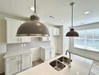 Modern kitchen with white cabinets, quartz countertops, and stylish pendant lights at 1796 Emory Ln # 100, Conyers, GA 30013