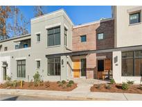 Modern townhome with light gray and brick exterior, wooden front door, and landscaping at 10871 Serenbe Ln, Chattahoochee Hills, GA 30268