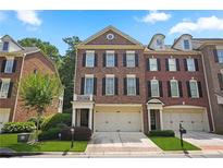 Brick three-story townhome with two-car garage and landscaped yard at 4740 Legacy Cove Ln, Mableton, GA 30126