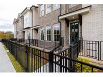 Brick townhouse exterior with a teal door and black metal fence at 616 Goldsmith Ct # 109, Johns Creek, GA 30022