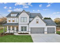 Two-story farmhouse with gray accents, three-car garage, and manicured lawn at 840 Porches Way, Dacula, GA 30019