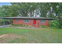 Brick ranch house exterior with a red door and a nicely landscaped yard at 2483 Crockett Se Dr, Marietta, GA 30067