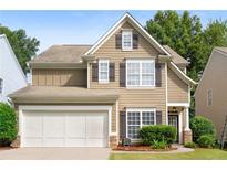 Two-story house with tan siding, white garage door, and dark shutters at 320 Pintail Ct, Suwanee, GA 30024