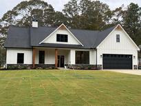 White farmhouse exterior with black accents, large windows, and a spacious lawn at 11 Harmony Ridge Dr, Temple, GA 30179