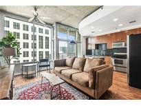 Modern living room with hardwood floors, exposed concrete, and city views at 943 Peachtree Ne St # 1107, Atlanta, GA 30309