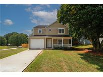 Tan two-story house with white garage door and porch at 707 Arbor Hill Dr, Stone Mountain, GA 30088