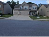 Two-story house with a three car garage and manicured lawn at 221 Eleanora Way, Loganville, GA 30052