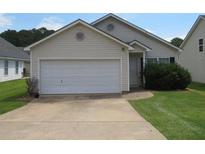 Beige house with a white garage door and well-maintained lawn at 435 Victoria Blvd, Oxford, GA 30054