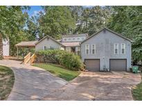 Gray two-story house with double garage, landscaped yard and a long driveway at 5833 Wind Haven Nw Ct, Kennesaw, GA 30152