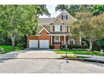 Two-story home with brick facade, two-car garage, and rocking chairs on porch at 738 Key Largo Ct, Auburn, GA 30011