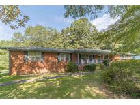 Brick ranch house with front porch, rocking chairs, and mature trees at 1645 Highpoint Rd, Snellville, GA 30078