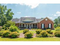 Brick house with a front porch, nicely landscaped lawn, and large windows at 12 Ivy Chase Nw Way, Cartersville, GA 30121