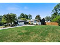 Ranch style home with a spacious lawn, attached garage, and wooden fence at 3573 Clubhouse Ln, Conyers, GA 30094
