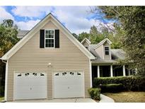 Two-story house with beige siding, two-car garage, and landscaping at 7025 Fletcher Dr, Winston, GA 30187
