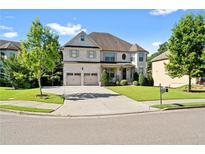 Two-story house with brick facade, three-car garage, and landscaped lawn at 4550 Fernbrook Pl, Cumming, GA 30040