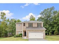 Two-story brick house with a white garage door and landscaping at 2320 Danielle Blvd, Conyers, GA 30012