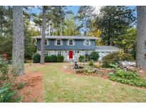 Gray house exterior with stone accents, red door, and landscaped yard at 4400 Huntington Cir, Dunwoody, GA 30338