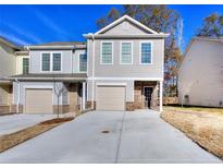 Two-story townhome with attached garage and brick accents at 6186 Ripple Way # 84, South Fulton, GA 30349