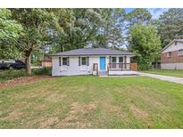 Charming ranch home with white exterior, blue door and landscaped lawn at 8376 Attleboro Dr, Jonesboro, GA 30238