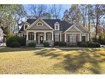Two-story house with stone accents, large front porch, and landscaped lawn at 403 Pebblebrooke Ln, Canton, GA 30115