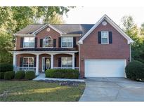 Brick two-story house with a white garage door and landscaping at 994 Rolling Forest Ln, Lilburn, GA 30047
