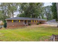 Brick ranch house with yellow shutters, large yard, and carport at 3689 Laurie Woods Ln, Decatur, GA 30034
