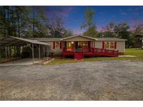 Mobile home with carport, red deck, and landscaped yard at 45 Harlan Lane Dr, Villa Rica, GA 30180