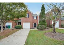 Brick townhouse with a two-car garage and a well-maintained lawn at 1628 River Main Ct, Lawrenceville, GA 30046