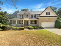 Two-story brick house with a front porch and attached garage, well-maintained at 156 Melrose Creek Dr, Stockbridge, GA 30281