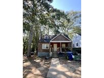 Ranch style home with wood siding and a covered porch, nestled among tall trees at 1876 Madrona Nw St, Atlanta, GA 30318