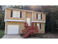 Tan two-story house with red stairs and attached garage at 5300 Forest Downs Ln, Atlanta, GA 30349