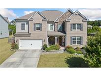 Two-story brick home with stone accents, large windows, and a landscaped yard at 5460 Vendelay Ln, Cumming, GA 30040