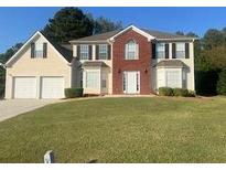 Two-story brick and siding house with a two-car garage and manicured lawn at 2608 Downing Park Se Dr, Conyers, GA 30094