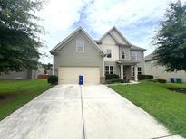 Two story house with gray siding, three car garage, and manicured lawn at 2469 Osceola Rd, Lithonia, GA 30058