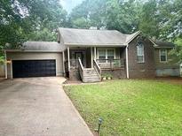 House exterior featuring a beige vinyl siding, black garage door, and a well-manicured lawn at 115 Elberta St, Mcdonough, GA 30253