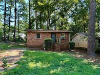 Brick cottage with a small front yard, steps to the entrance and mature trees surrounding the property at 435 Warren Ave, Scottdale, GA 30079