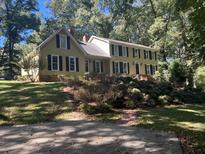 Two story home with a yellow exterior, black shutters, and a large yard at 3656 Rainbow Cir, Snellville, GA 30039