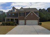 Two-story brick home with a three-car garage and landscaped front yard at 1437 Bourdon Bell Dr, Conyers, GA 30013