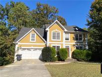 Two-story house with a yellow facade, white garage door, and landscaping at 1965 Tyler Trce, Lawrenceville, GA 30043