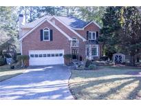 Brick house with a two-car garage and landscaped yard at 1563 Poplarwood Nw Ln, Lawrenceville, GA 30043