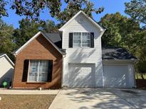 Two-story house with brick and white vinyl siding, two-car garage, and landscaping at 3423 Homeward Trl, Ellenwood, GA 30294